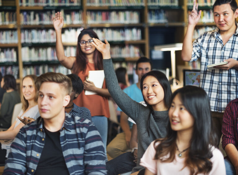 Students in class raising hands.