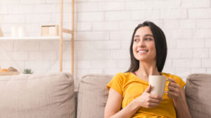 A student sitting on a couch with a cup