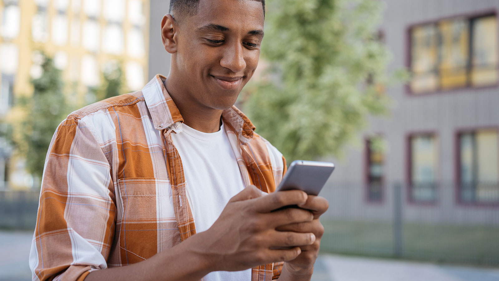 Student standing on campus with phone