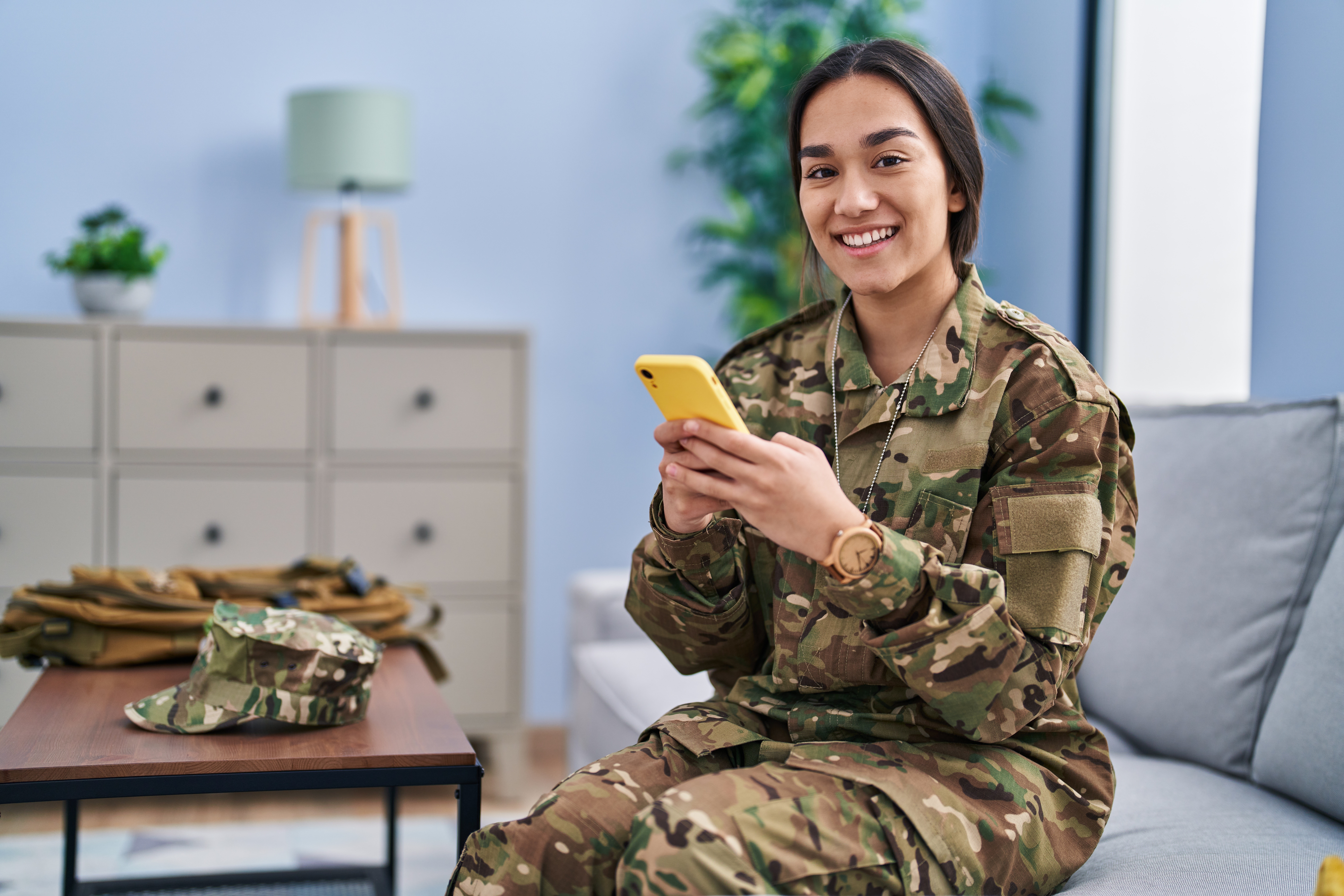 Female soldier in army uniform holding a smartphone and smiling
