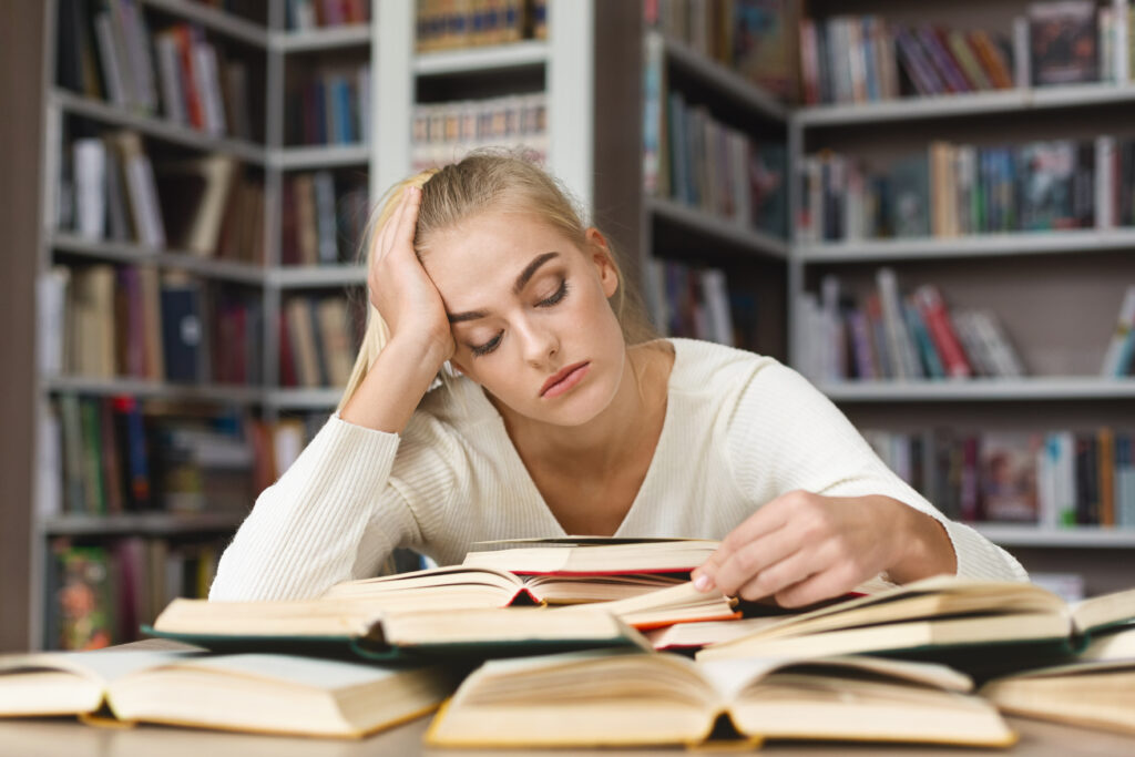 Stressed student in library reading a book