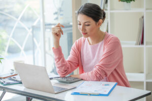 Business,Woman,Looking,A,Calculator,For,Calculate,On,Desk,In