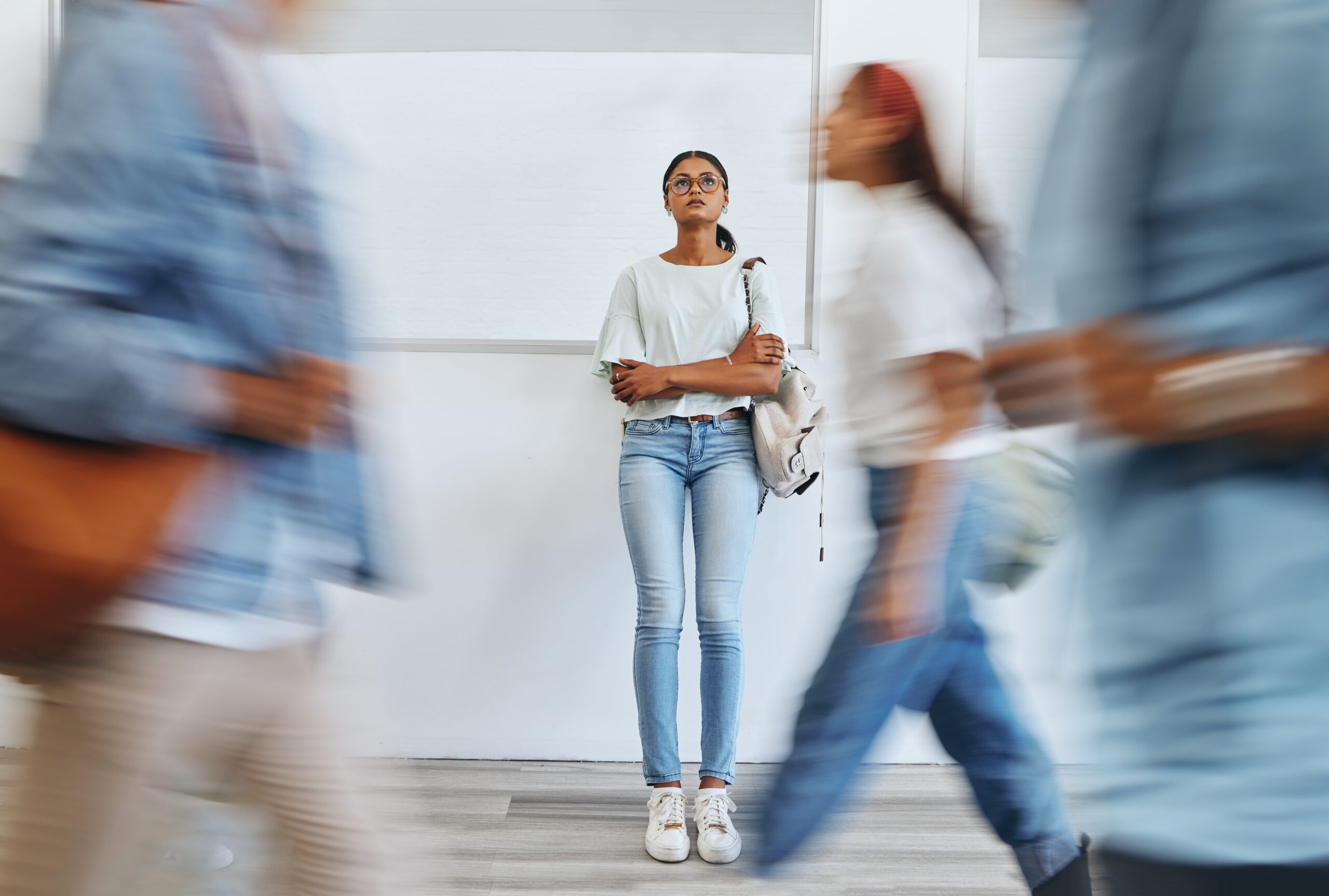 Student stands still in a hallway as other students move around her