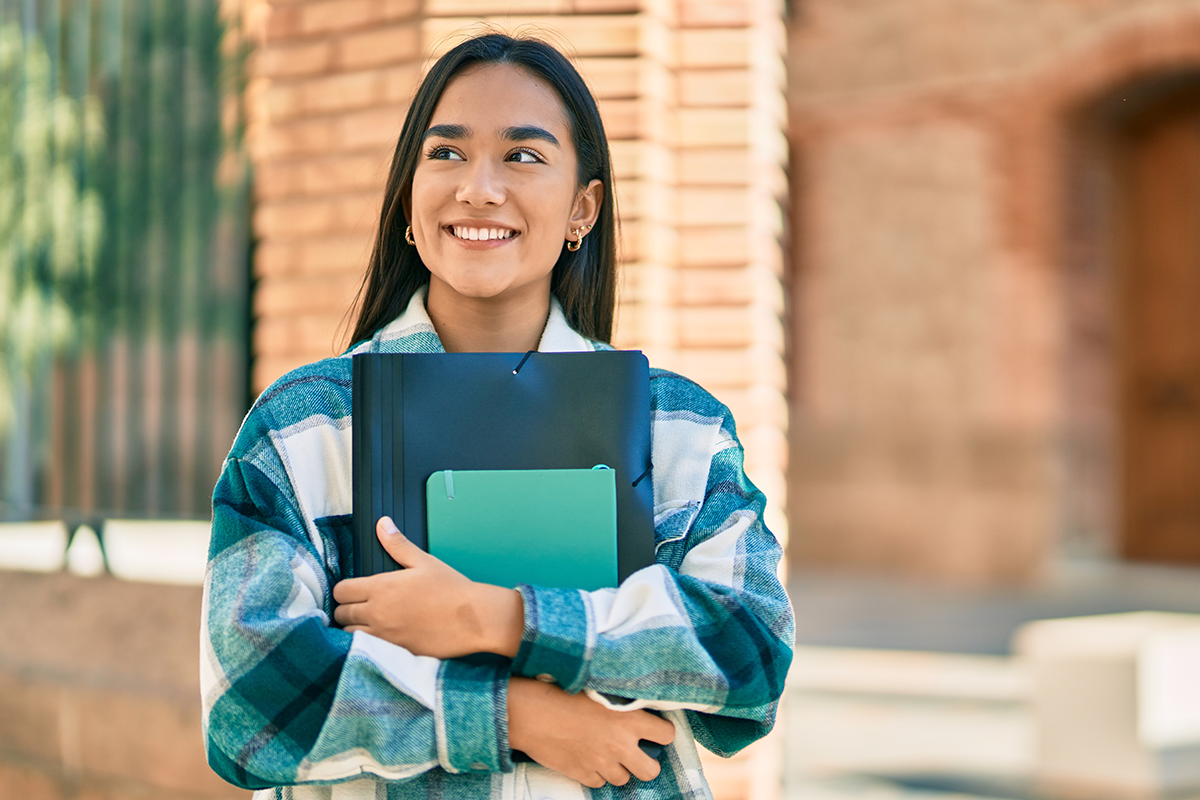 College student standing on campus holding notebook