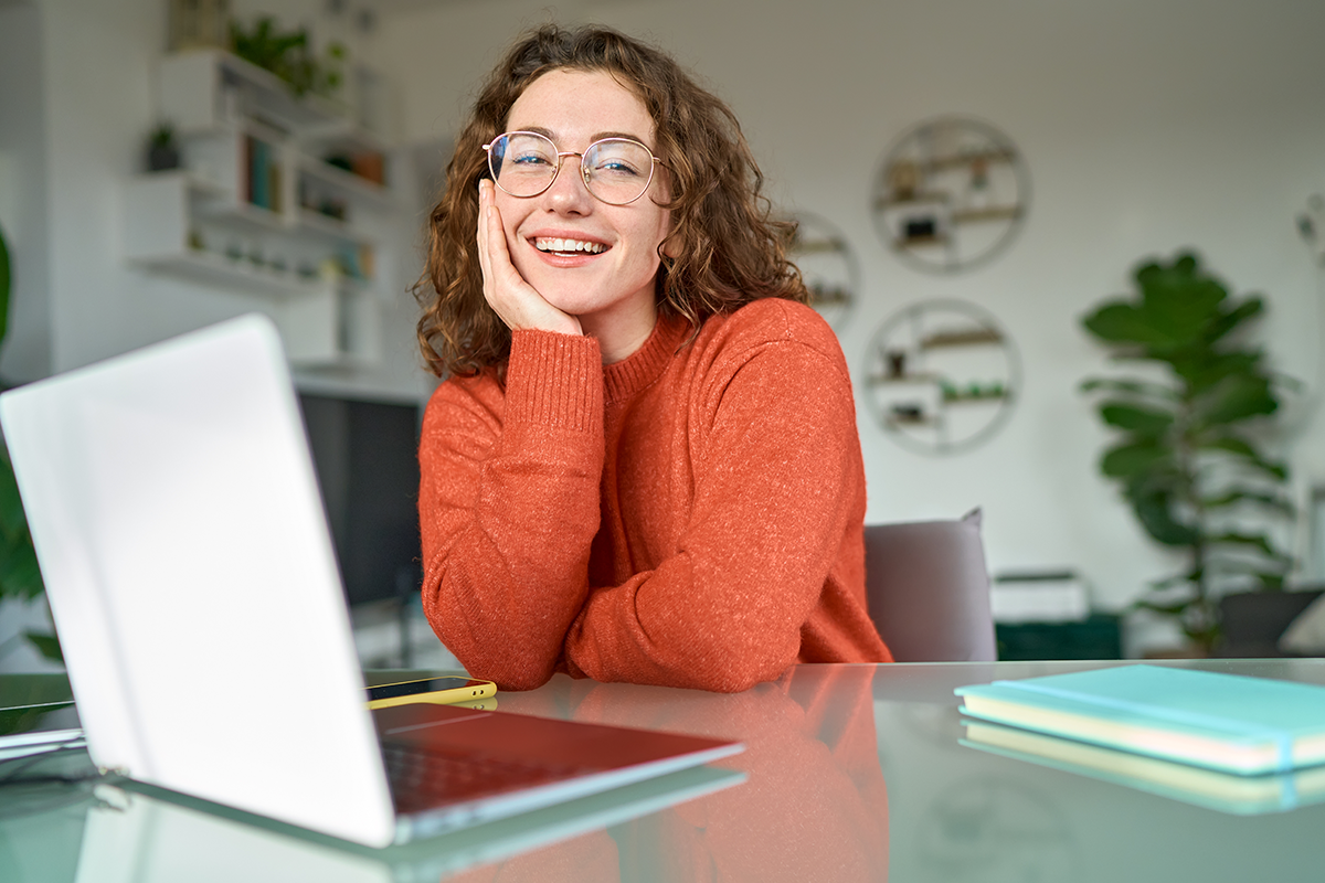 College student sitting at desk with phone and computer