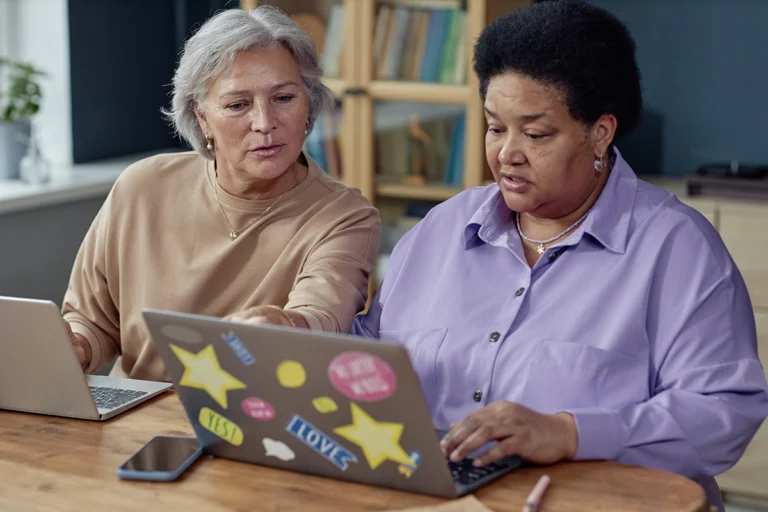 Portrait of two senior women using laptops