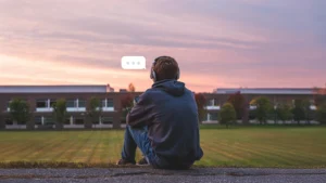 College student sitting on grass and looking at phone