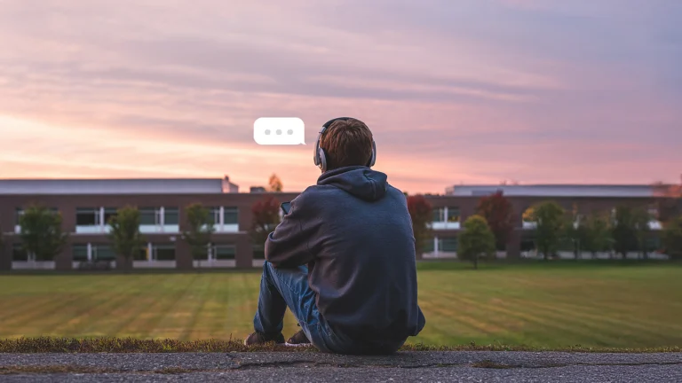 College student sitting on grass and looking at phone