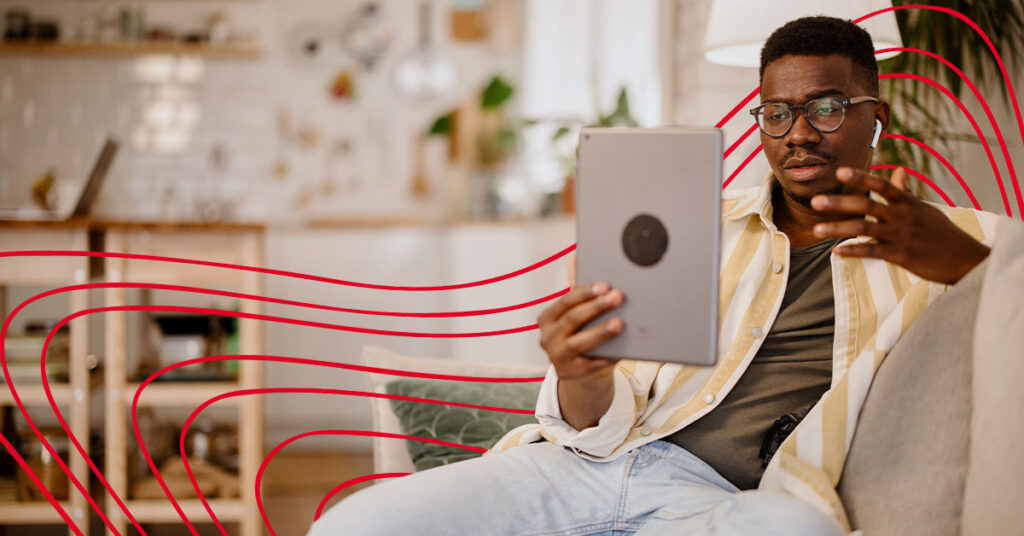 Male student sits on couch while video chatting on his iPad