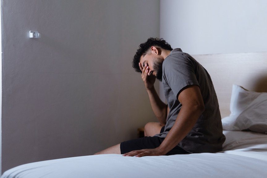 Student in distress sits with his head in his hand.