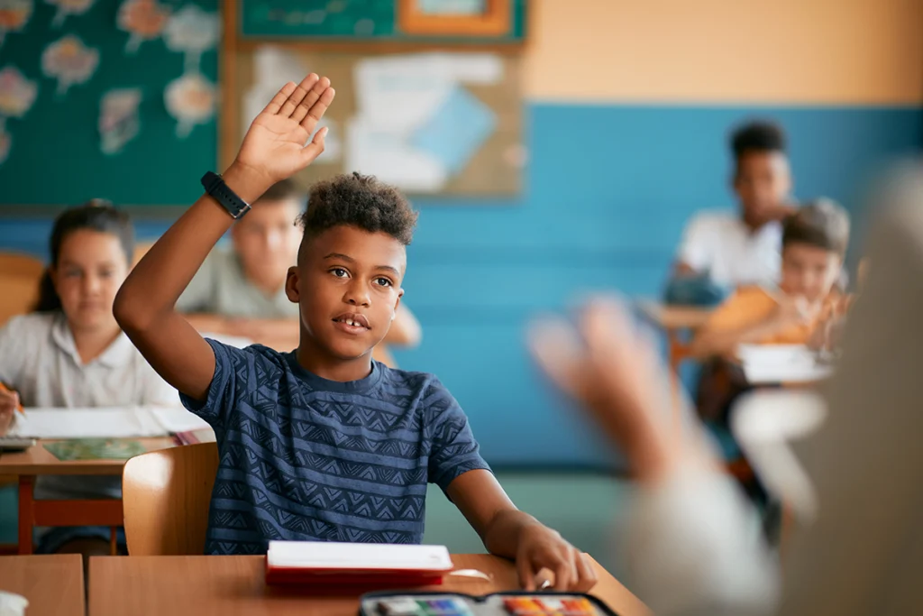 Elementary school student in class with hand raised