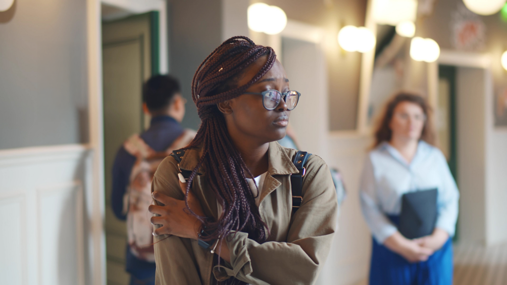 female student stands downcast in the hallway